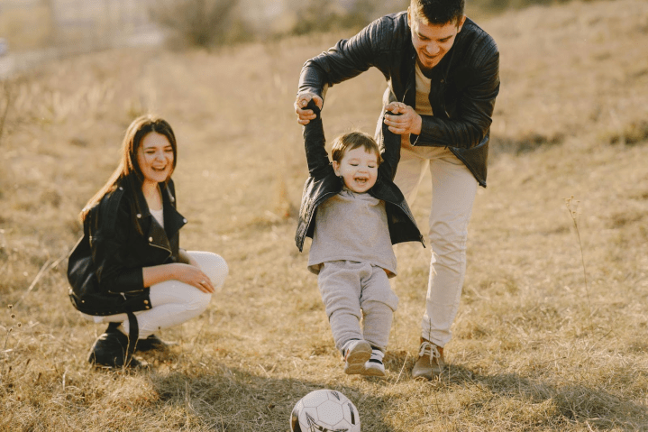 Smiling parents playing with their young child outdoors, enjoying quality time together after a successful weight loss journey.